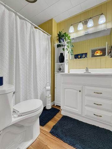 bathroom featuring vanity, hardwood / wood-style flooring, toilet, and wood walls