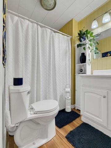 bathroom with hardwood / wood-style floors, wooden walls, and toilet