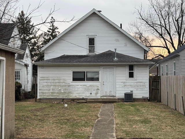 rear view of property with cooling unit and a lawn