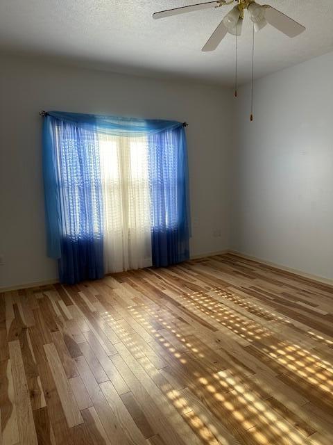 empty room featuring wood-type flooring, ceiling fan, and a textured ceiling