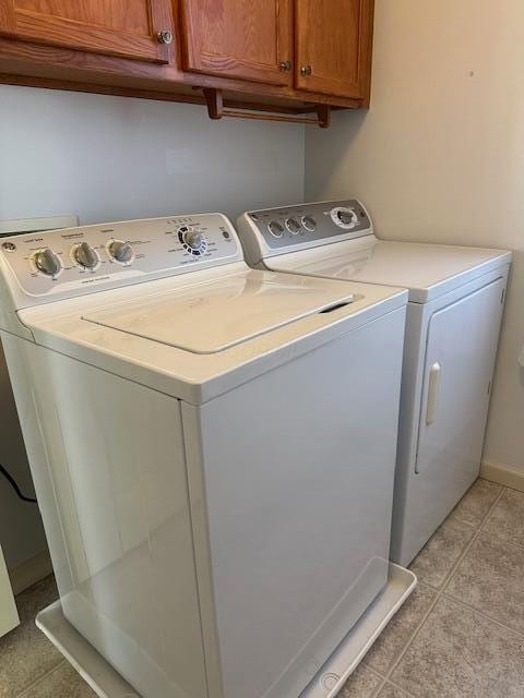 laundry room featuring cabinets, light tile patterned floors, and independent washer and dryer