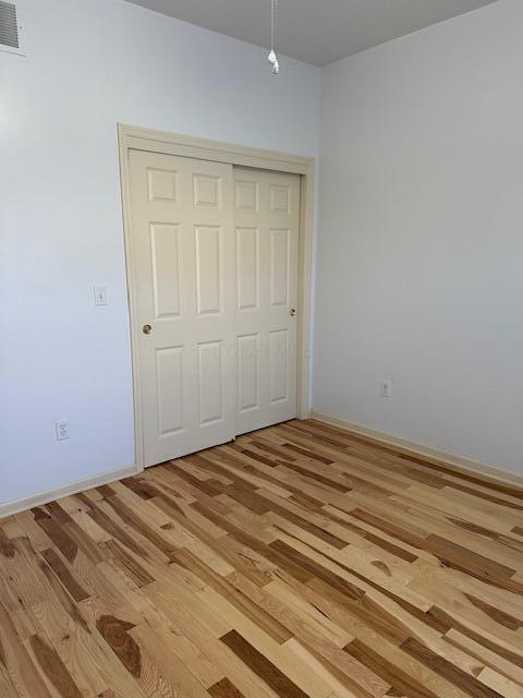 unfurnished bedroom with a closet and light wood-type flooring