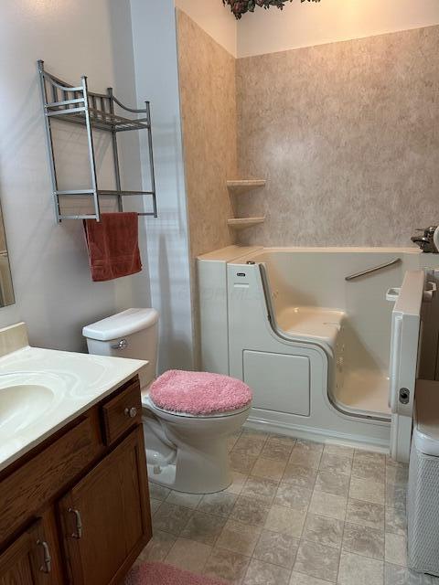 bathroom with vanity, toilet, and a washtub