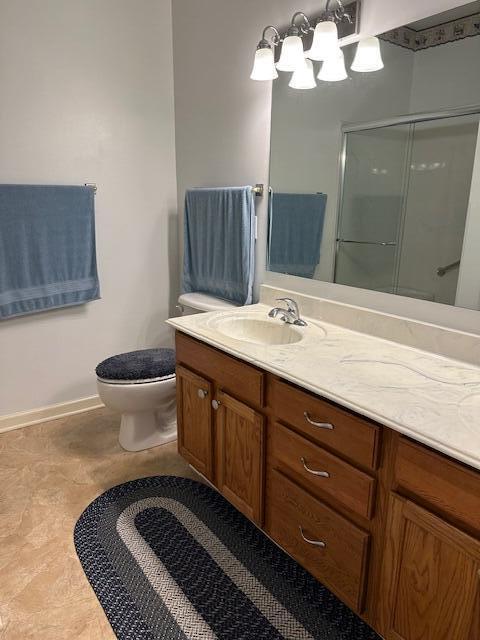 bathroom with vanity, tile patterned flooring, a shower with shower door, and toilet