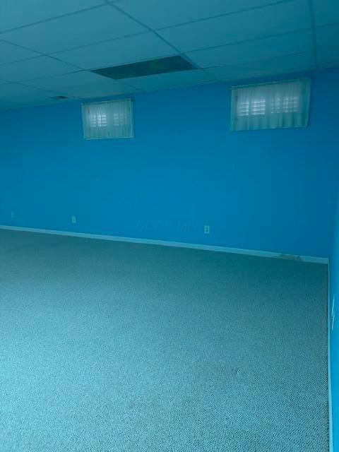 basement featuring a paneled ceiling and carpet flooring