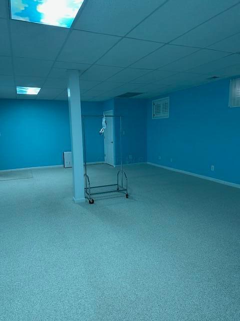 basement with a paneled ceiling and carpet flooring