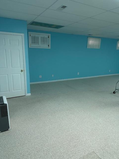 basement featuring a paneled ceiling and carpet flooring