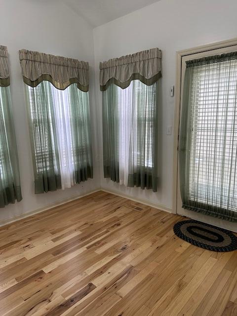 unfurnished dining area with wood-type flooring and vaulted ceiling