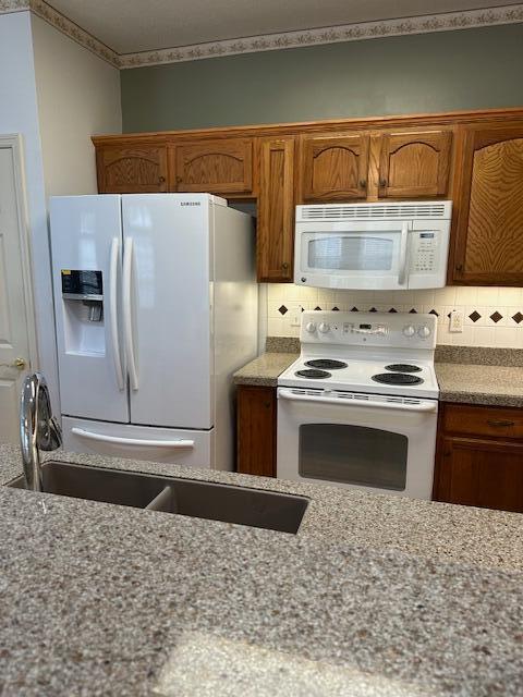 3 Claire Ct, Circleville, OH 43113 - kitchen with white appliances, brown cabinetry, decorative backsplash, and light stone countertops