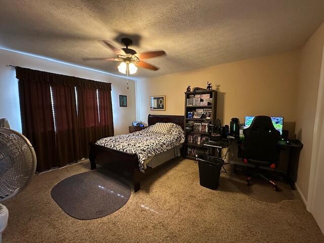 carpeted bedroom with ceiling fan and a textured ceiling