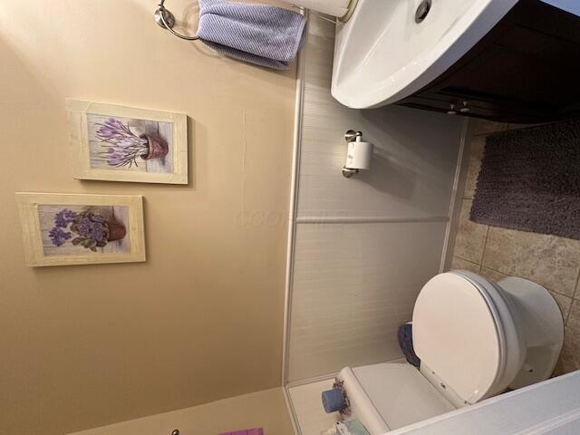 bathroom featuring toilet and tile walls