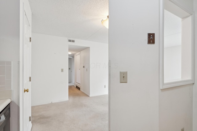 corridor with light carpet and a textured ceiling