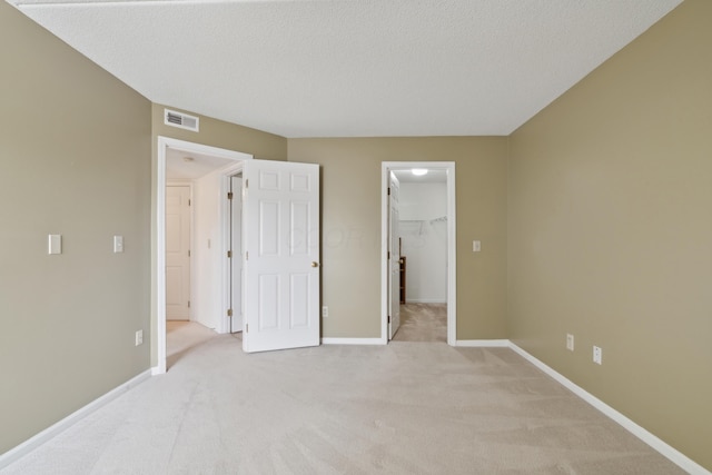 carpeted bedroom featuring a spacious closet, a closet, and a textured ceiling