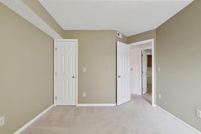 unfurnished bedroom featuring light colored carpet and a textured ceiling