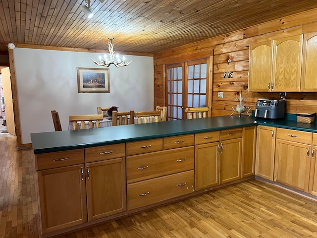 kitchen with pendant lighting, wood walls, wood ceiling, light hardwood / wood-style floors, and an inviting chandelier