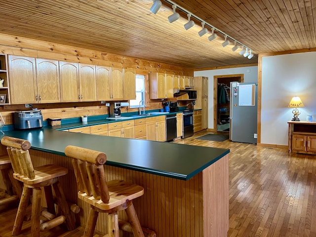 kitchen featuring stainless steel appliances, a kitchen bar, sink, and light wood-type flooring