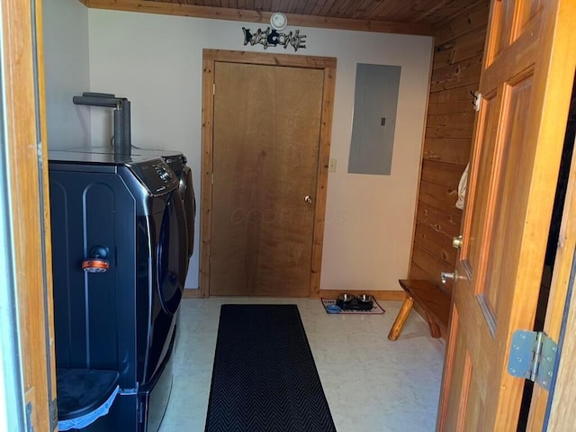 clothes washing area featuring wood ceiling, wooden walls, electric panel, and washing machine and dryer