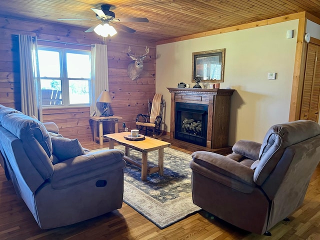 living room featuring ceiling fan, dark wood-type flooring, wooden ceiling, and wooden walls