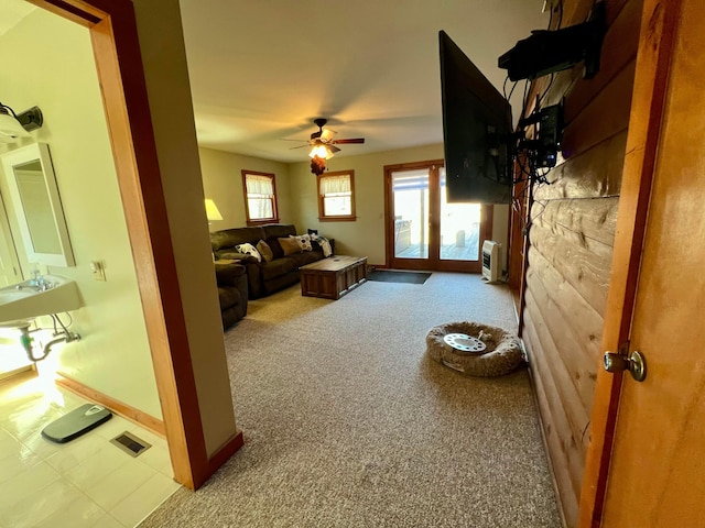 living room with heating unit, light colored carpet, and ceiling fan