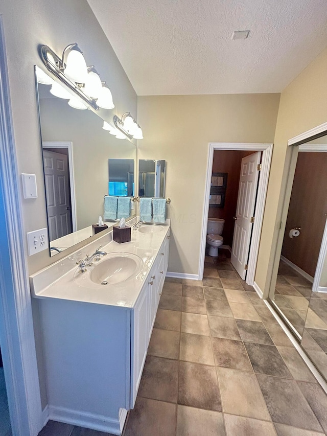 bathroom with vanity, tile patterned floors, a textured ceiling, and toilet