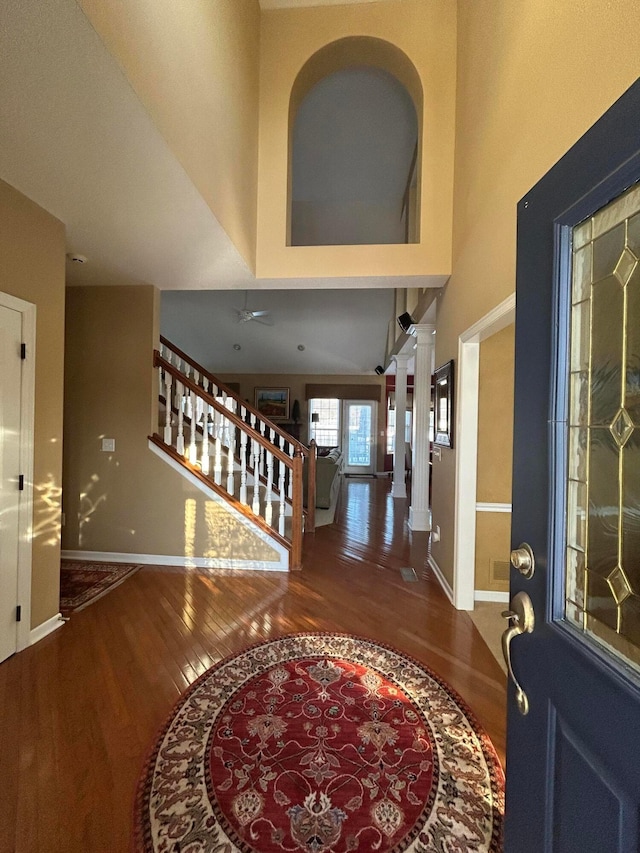 entrance foyer with a towering ceiling, wood-type flooring, and decorative columns