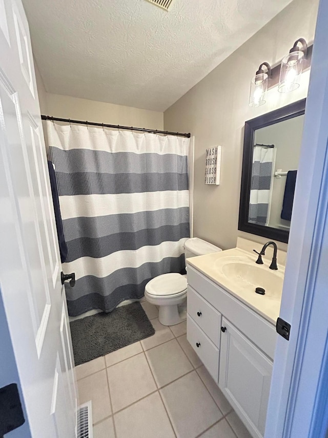 bathroom with vanity, tile patterned flooring, toilet, and a textured ceiling