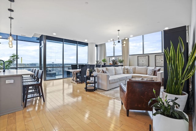 living room featuring a water view, floor to ceiling windows, a chandelier, and light hardwood / wood-style flooring