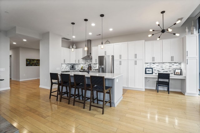 kitchen featuring decorative light fixtures, white cabinetry, a large island, stainless steel fridge with ice dispenser, and light wood-type flooring