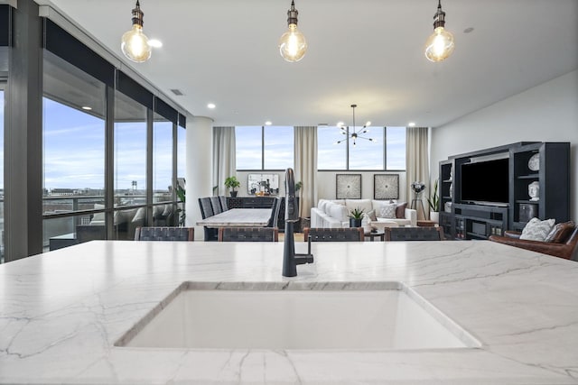 kitchen with pendant lighting, floor to ceiling windows, sink, and a notable chandelier