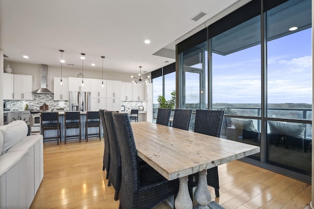 dining room with floor to ceiling windows, a chandelier, and light hardwood / wood-style floors