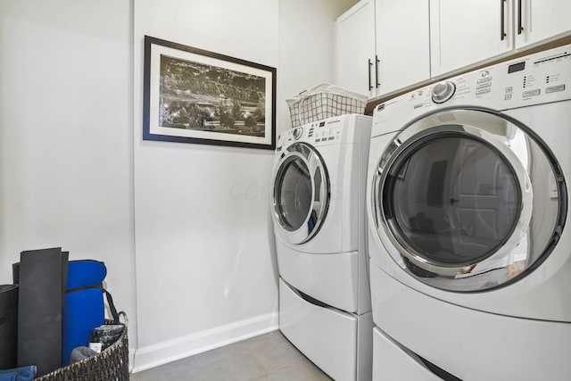 clothes washing area featuring cabinets and washing machine and clothes dryer