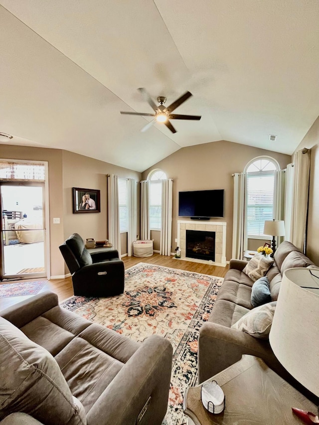 living room featuring ceiling fan, lofted ceiling, a fireplace, and light hardwood / wood-style floors