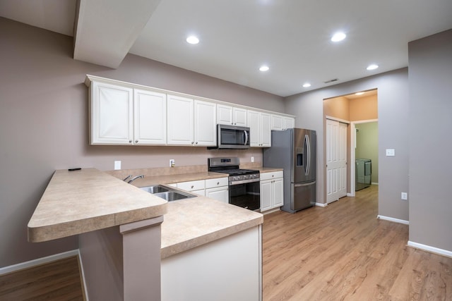 1240 Paddock Loop, Washington Court House, OH 43160 - kitchen with stainless steel appliances, a sink, washing machine and clothes dryer, a peninsula, and light countertops