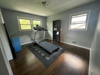 workout area with dark hardwood / wood-style floors and a healthy amount of sunlight