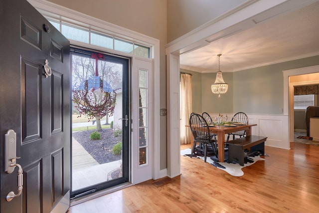 foyer entrance featuring ornamental molding, an inviting chandelier, and light hardwood / wood-style floors