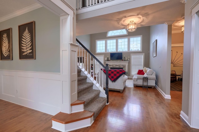 foyer with hardwood / wood-style flooring, ornate columns, ornamental molding, and a notable chandelier