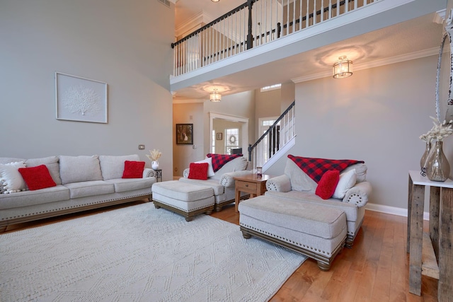 living room with crown molding, hardwood / wood-style flooring, and a towering ceiling