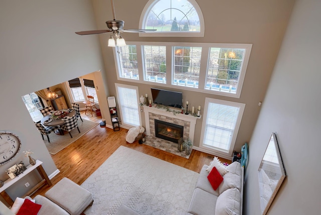 living room with light hardwood / wood-style flooring, ceiling fan, and a high ceiling