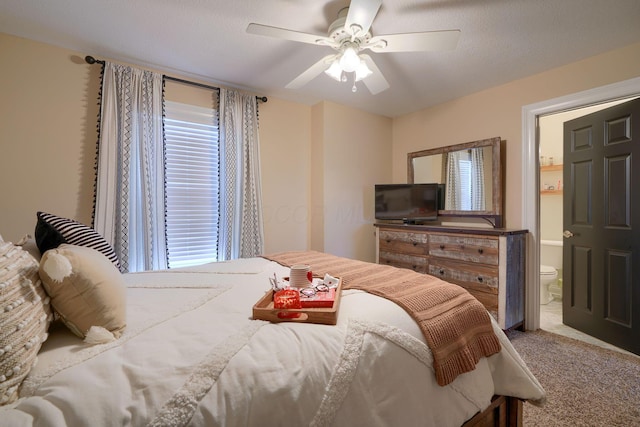 carpeted bedroom featuring ceiling fan and ensuite bath