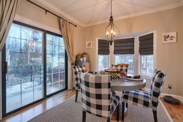 dining room featuring hardwood / wood-style flooring, ornamental molding, and a notable chandelier