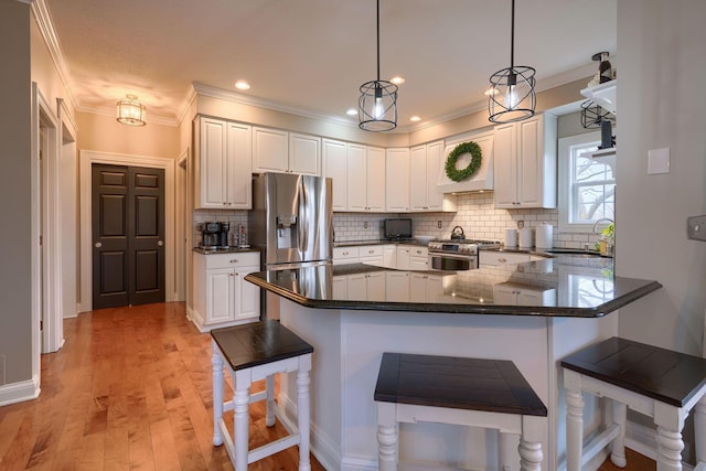 kitchen with sink, a breakfast bar area, hanging light fixtures, appliances with stainless steel finishes, and kitchen peninsula