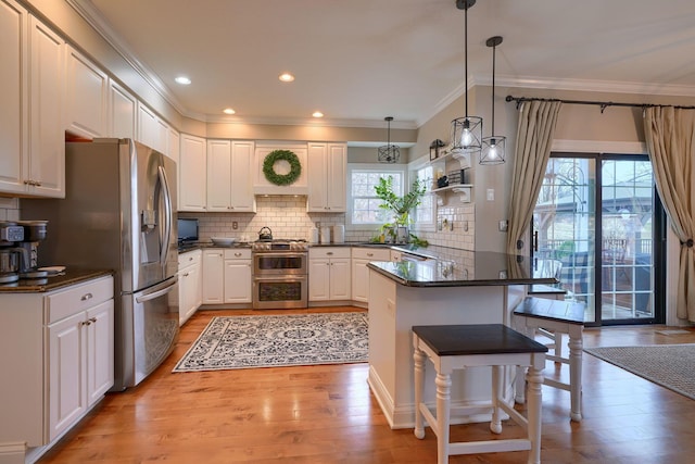 kitchen featuring pendant lighting, stainless steel appliances, a breakfast bar, and white cabinets