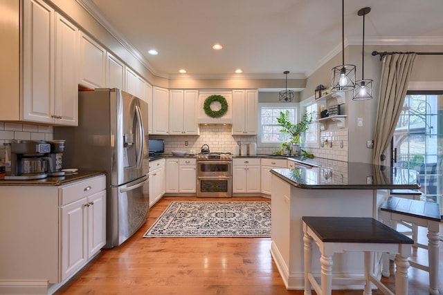 kitchen with white cabinetry, a breakfast bar area, kitchen peninsula, and appliances with stainless steel finishes