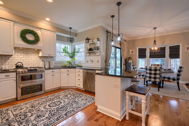 kitchen with appliances with stainless steel finishes, pendant lighting, white cabinets, and kitchen peninsula