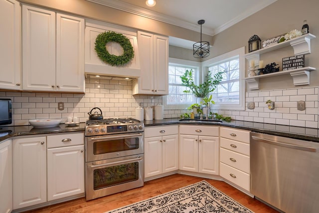 kitchen with pendant lighting, white cabinetry, stainless steel appliances, ornamental molding, and light hardwood / wood-style floors