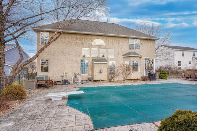 back of house featuring a covered pool and a patio