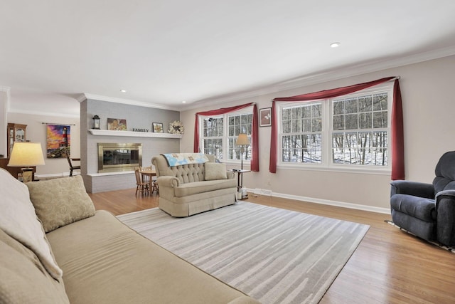 living room featuring ornamental molding, a fireplace, and light hardwood / wood-style flooring