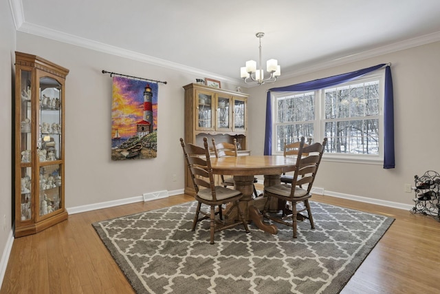 dining room featuring wood-type flooring, ornamental molding, and a chandelier