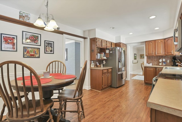 dining area featuring sink, light hardwood / wood-style flooring, and a notable chandelier