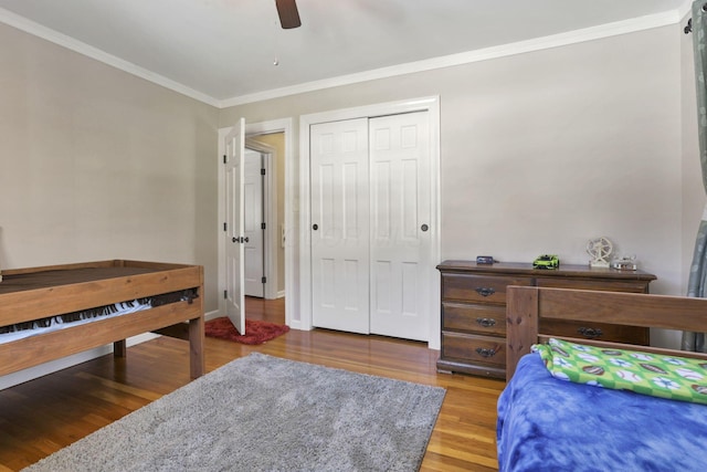 bedroom featuring wood-type flooring, ceiling fan, crown molding, and a closet